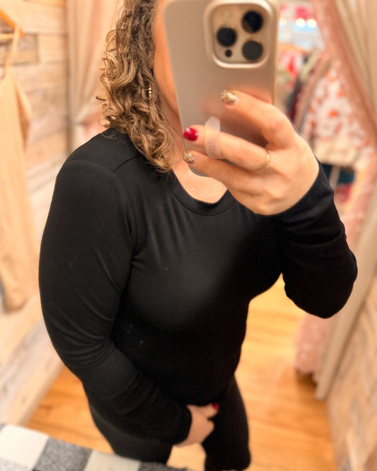 Person wearing a black long-sleeve top taking a mirror selfie.