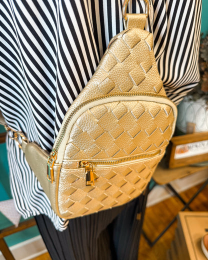 Gold quilted sling bag worn by a person with a striped shirt in the background
