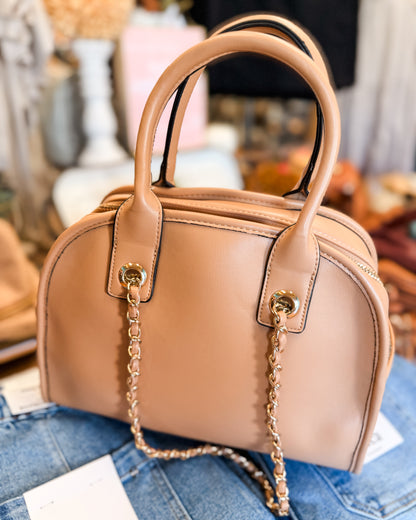 Tan handbag with a chain detail on a blue denim surface