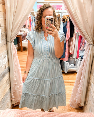 a striped tiered midi style dress with piping details and side pockets with a flutter cap sleeve