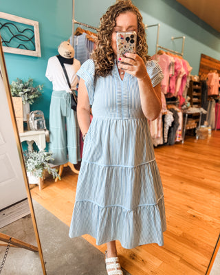 A striped tiered midi style dress with cap sleeves and piping details