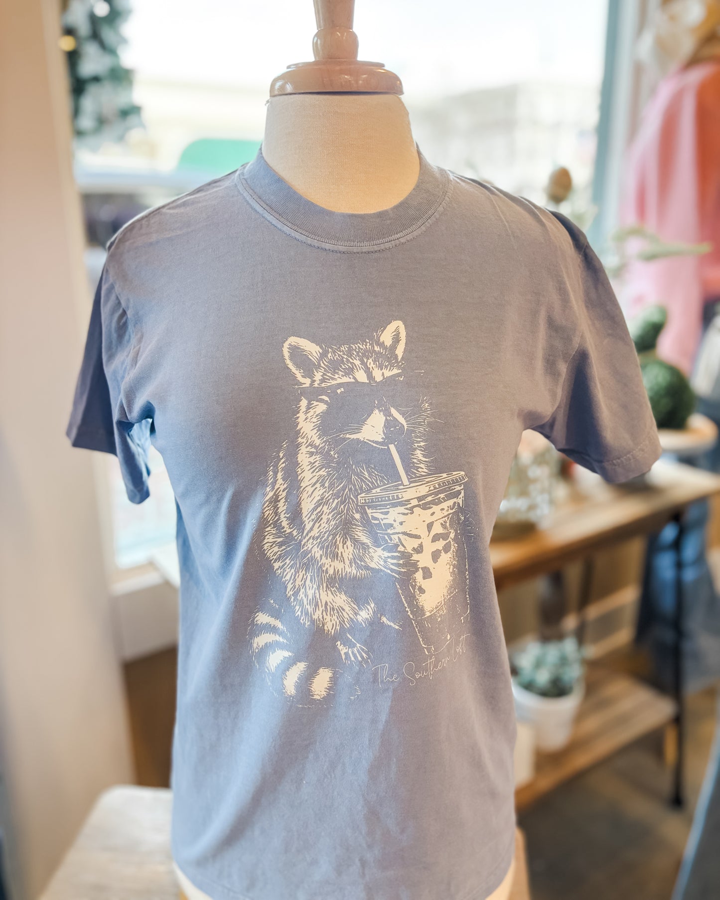A racoon sipping iced coffee on a graphic tshirt