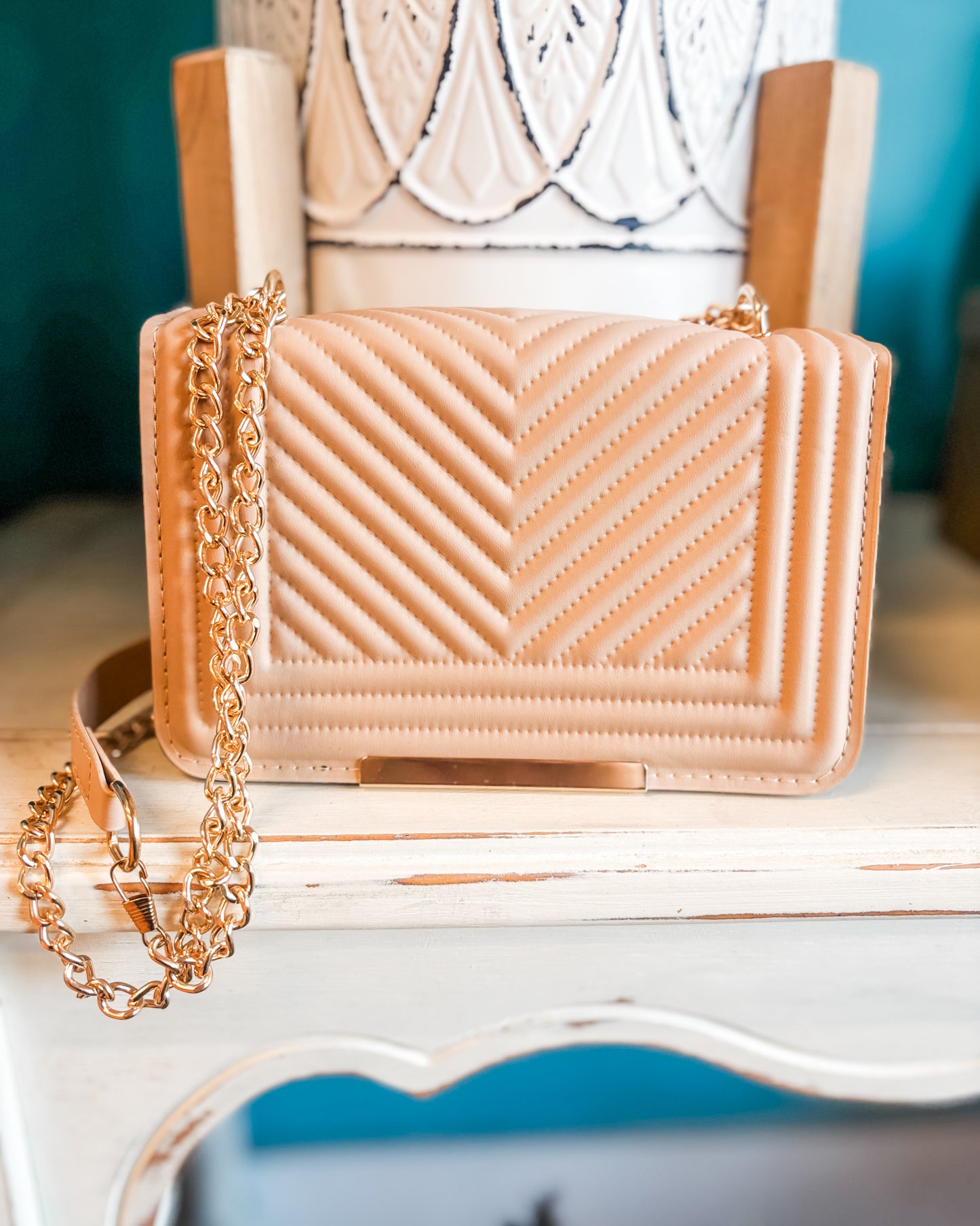 Pink handbag with gold chain on a decorative chair