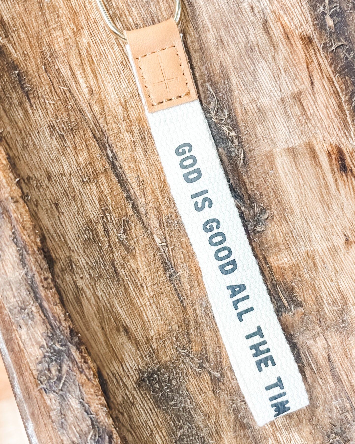 Keychain with 'God is Good All the Time' text on a wooden surface