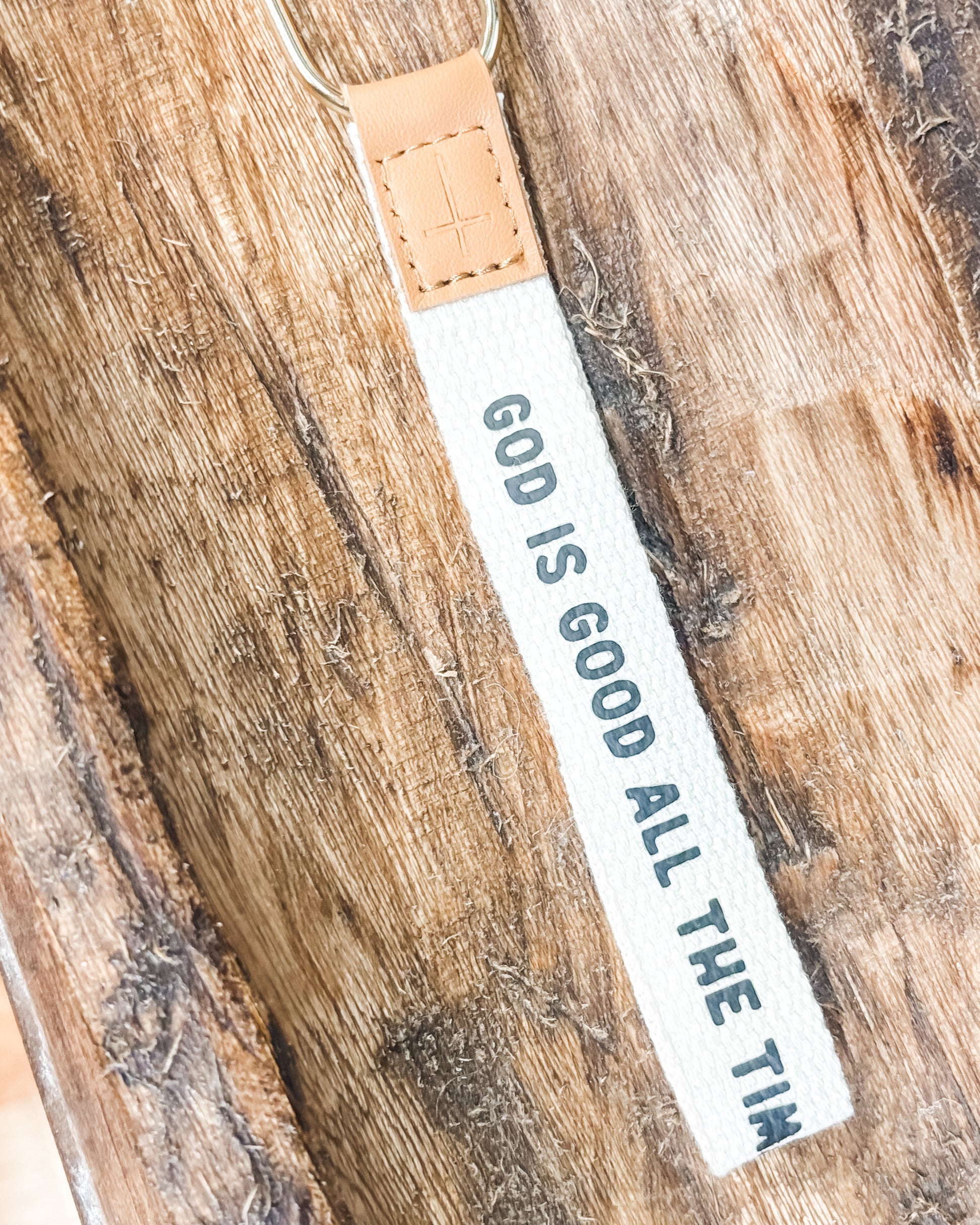 Keychain with 'God is Good All the Time' text on a wooden surface