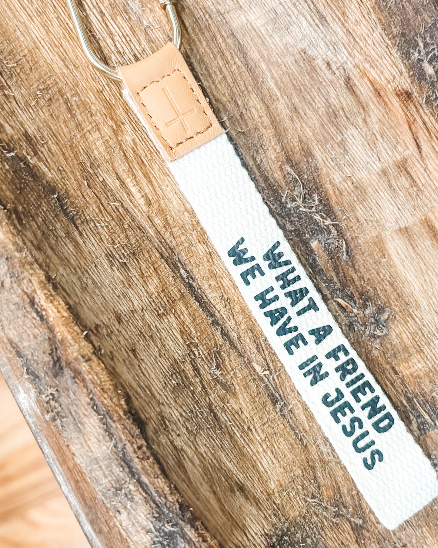 White strap with text 'What a friend we have in Jesus' on a wooden surface