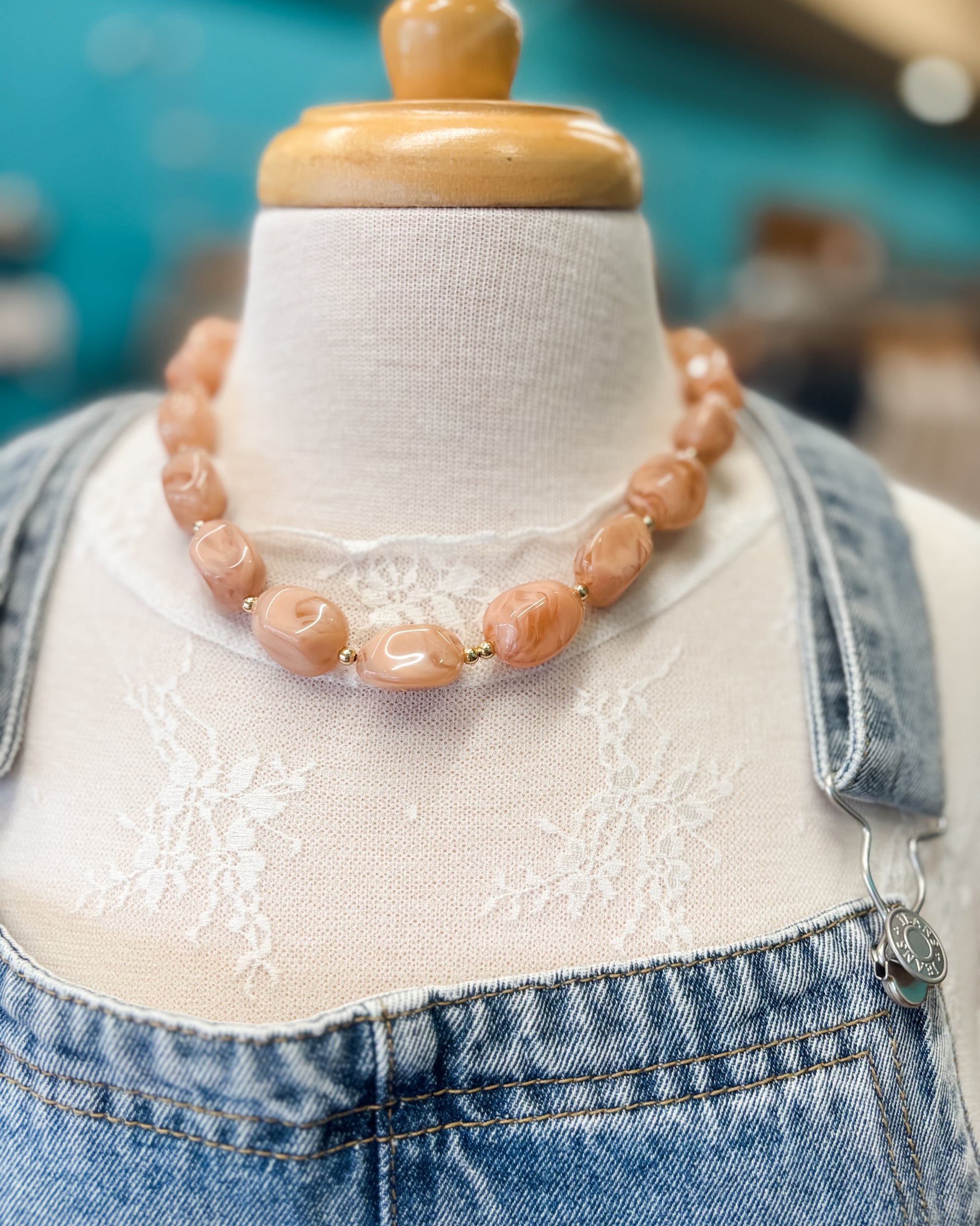 Necklace on a mannequin with denim jacket against a blurred background