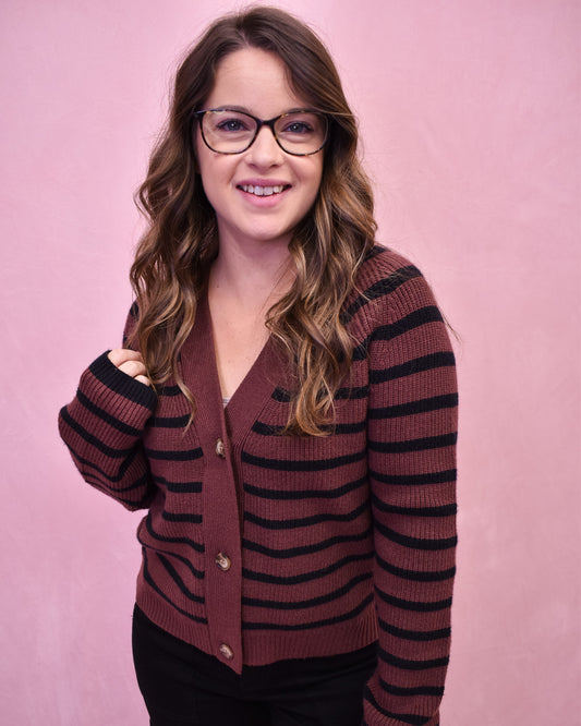 Woman wearing a striped cardigan against a pink background