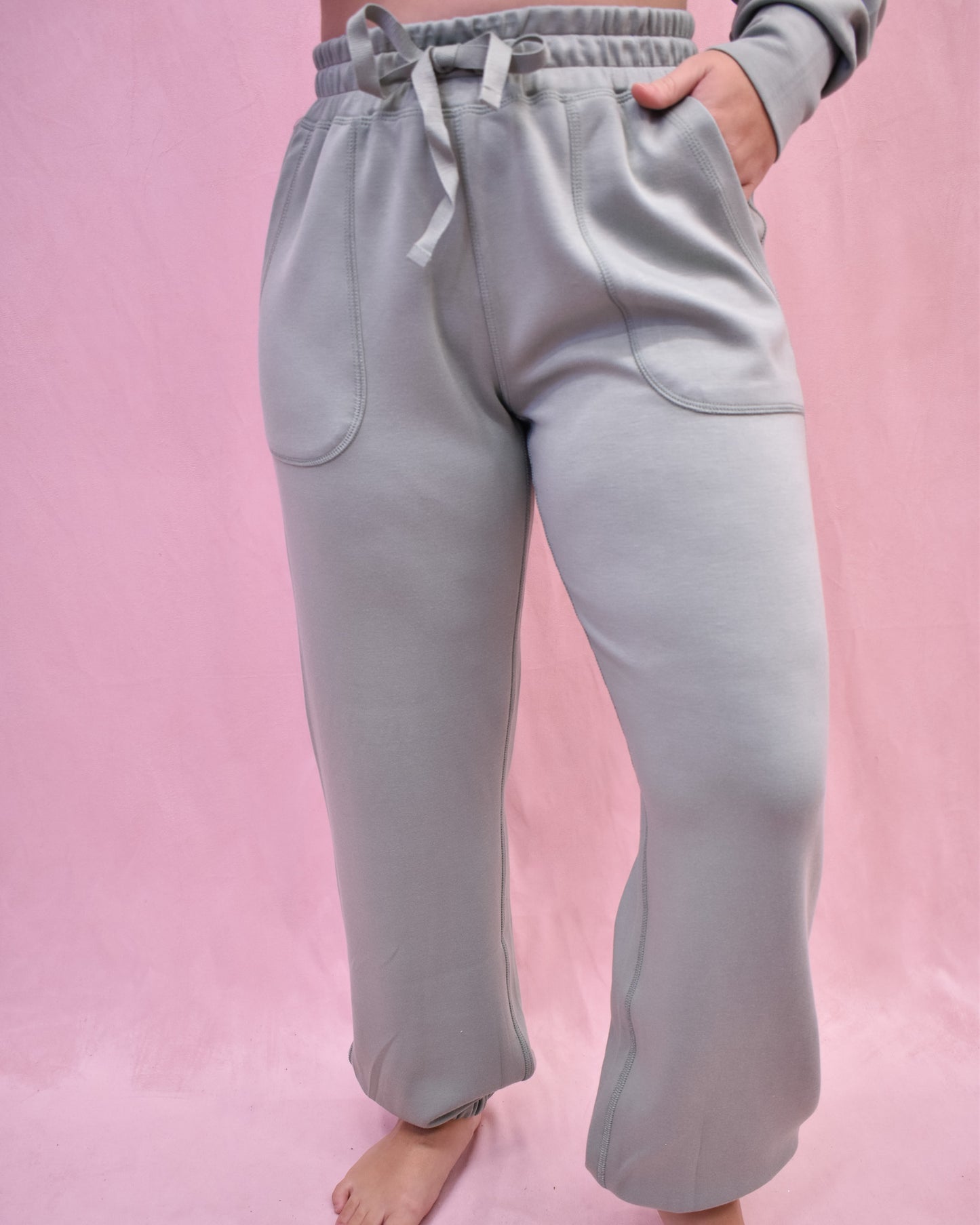 Light gray sweatpants worn by a person on a pink background