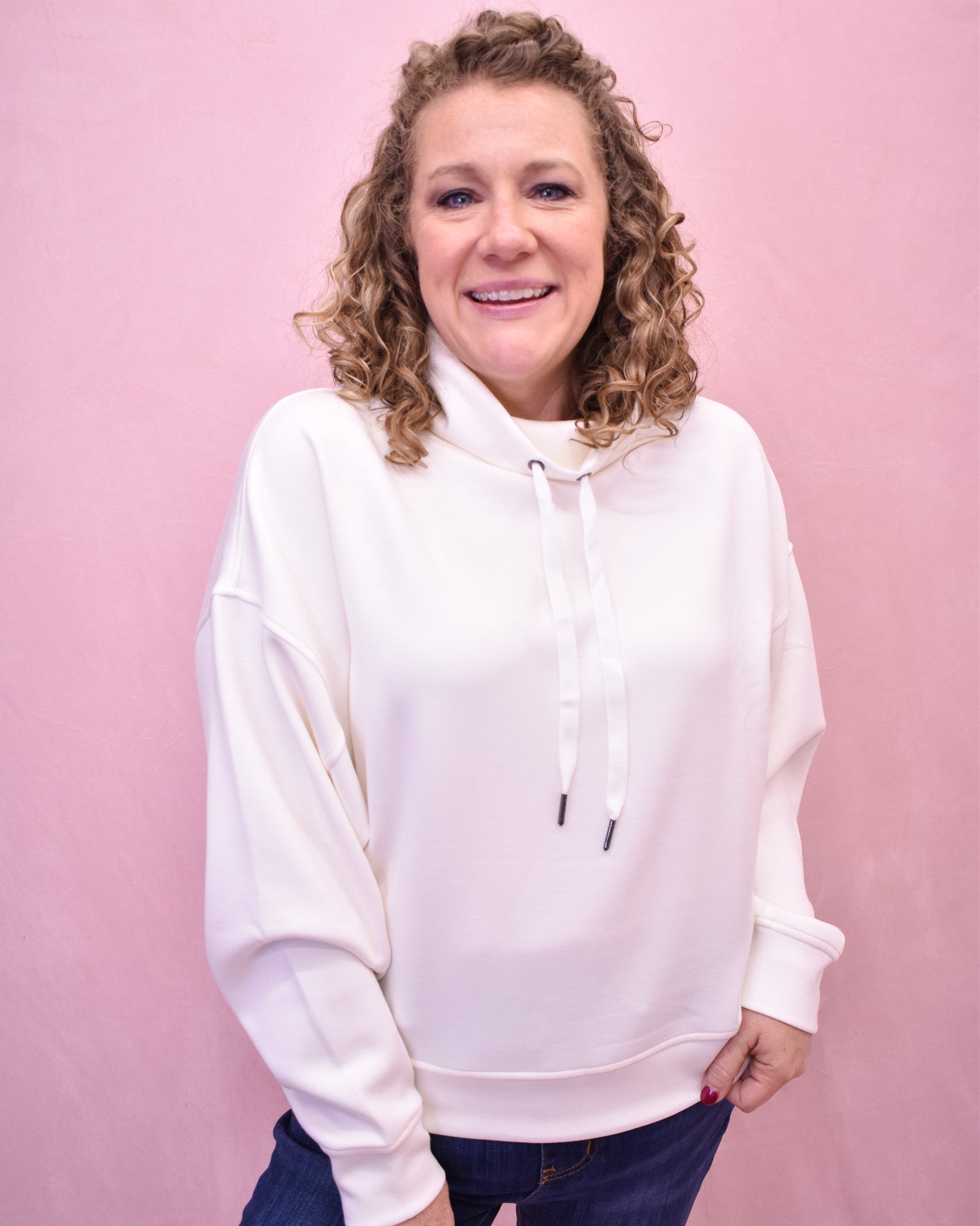 Woman wearing a white hoodie against a pink background