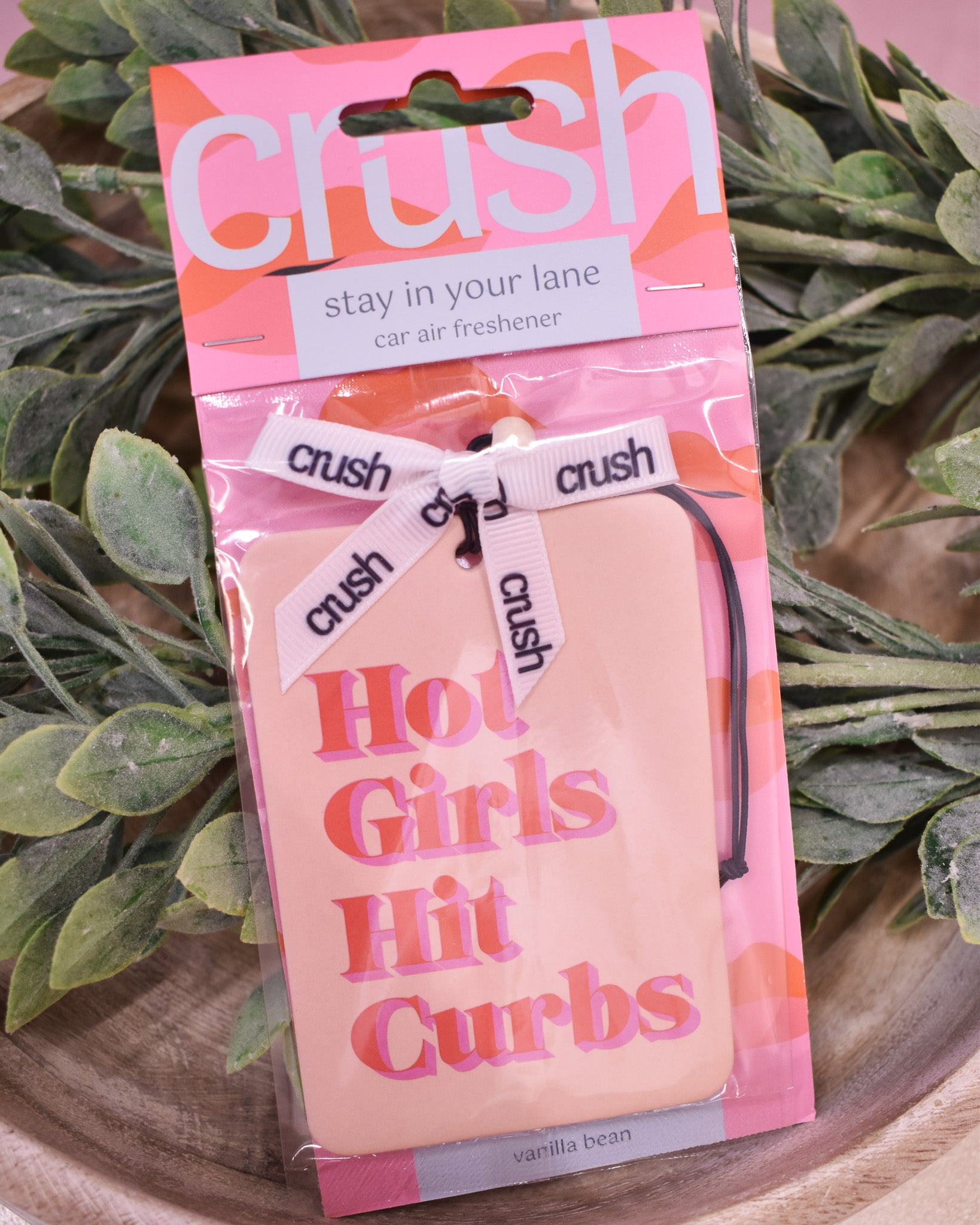 Packaged car air freshener with 'crush' branding and humorous text on a leafy background