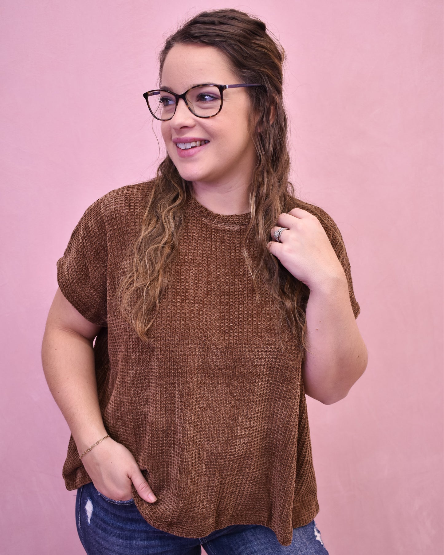 Woman wearing a brown sweater against a pink background