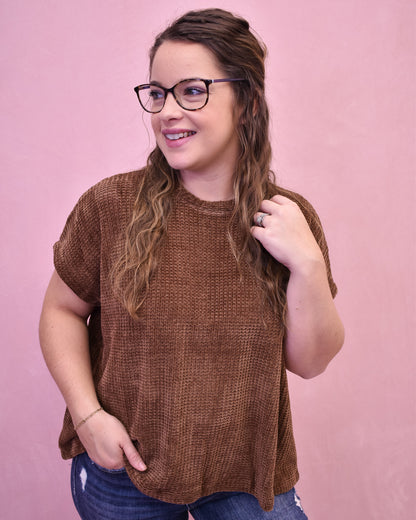 Woman wearing a brown sweater against a pink background