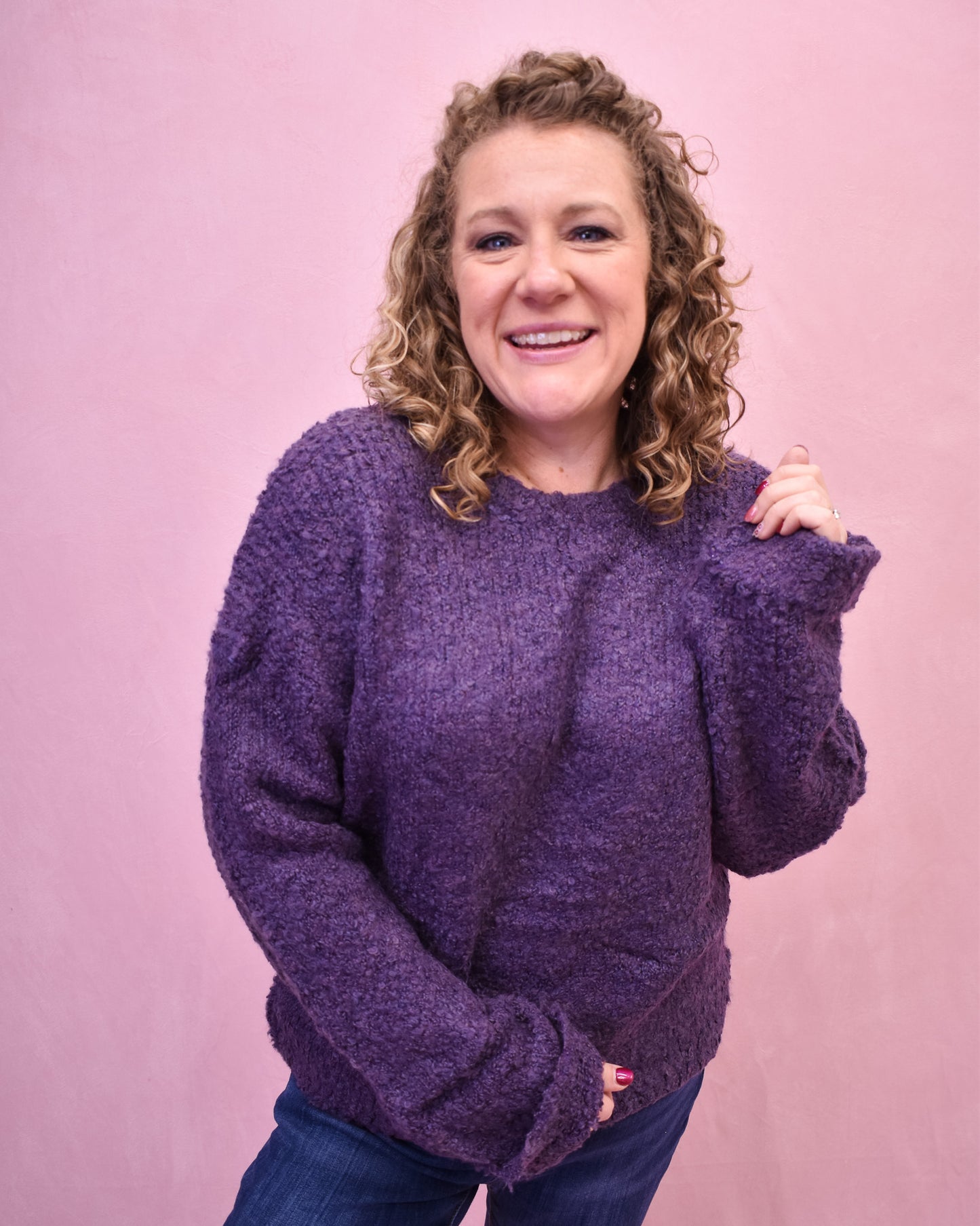 Woman wearing a purple sweater against a pink background