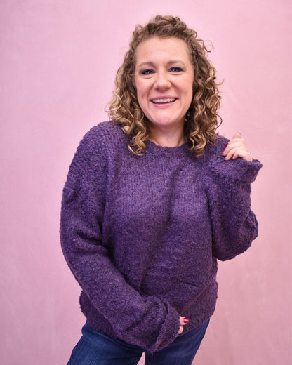 Woman wearing a purple sweater against a pink background