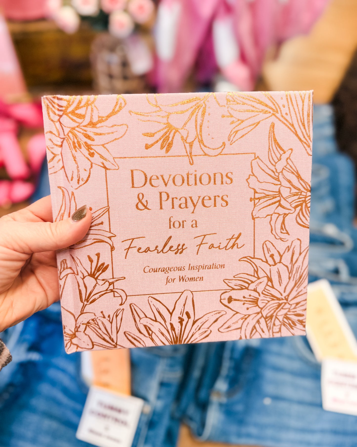 Book titled 'Devotions & Prayers for a Fearless Faith' held by a person with a floral design on the cover.