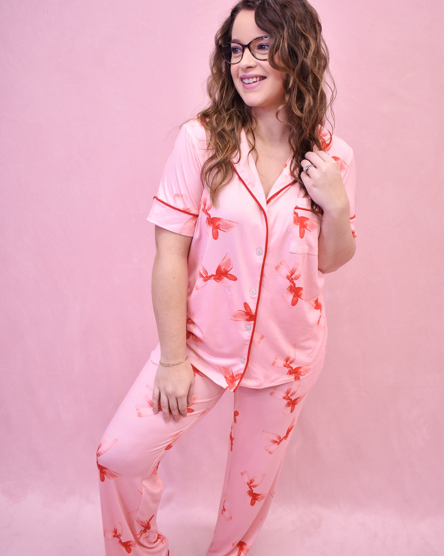 Woman wearing pink pajamas with red floral patterns on a pink background