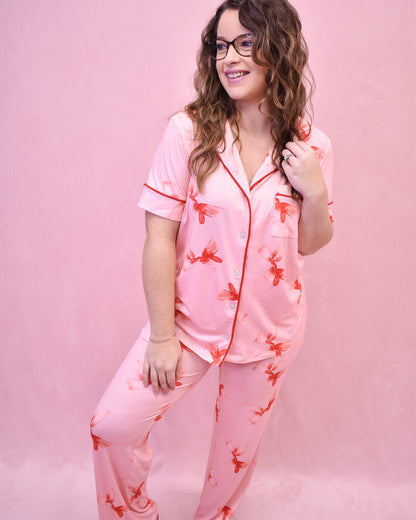 Woman wearing pink pajamas with red floral patterns on a pink background