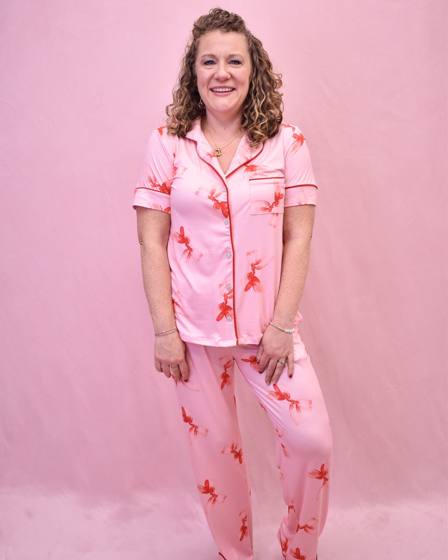 Woman wearing a pink floral pajama set against a pink background