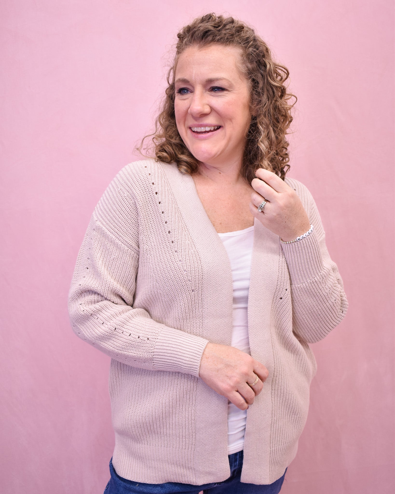 Woman wearing a light pink cardigan against a pink background