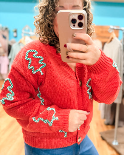 Person wearing a red sweater with green patterns, taking a mirror selfie.