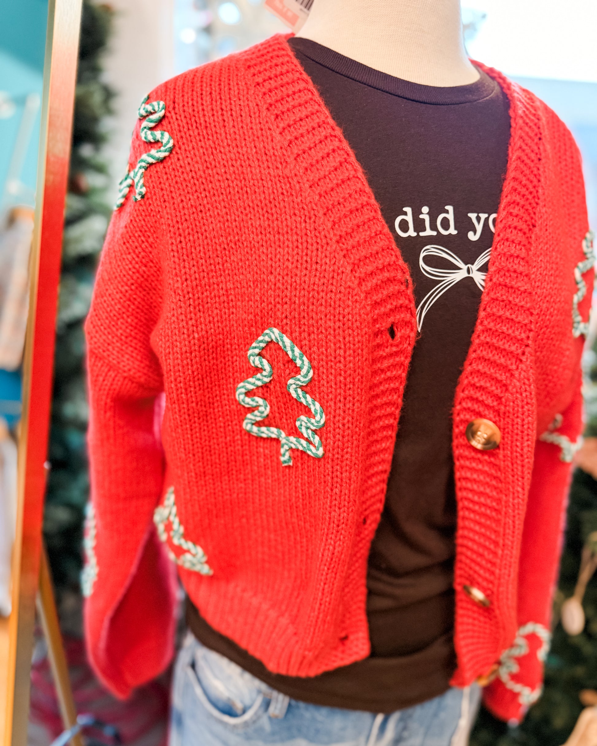 Red knitted cardigan with decorative elements over a dark shirt.