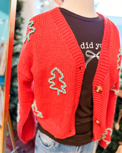 Red knitted cardigan with decorative elements over a dark shirt.