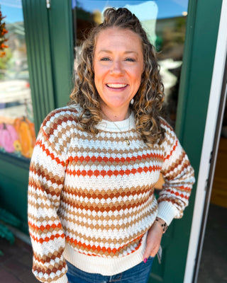 An orange cream and tan striped textured cable knit sweater