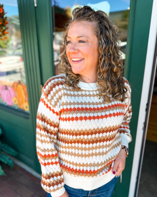 An orange cream and tan striped textured cable knit sweater
