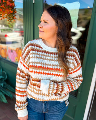 An orange cream and tan striped textured cable knit sweater
