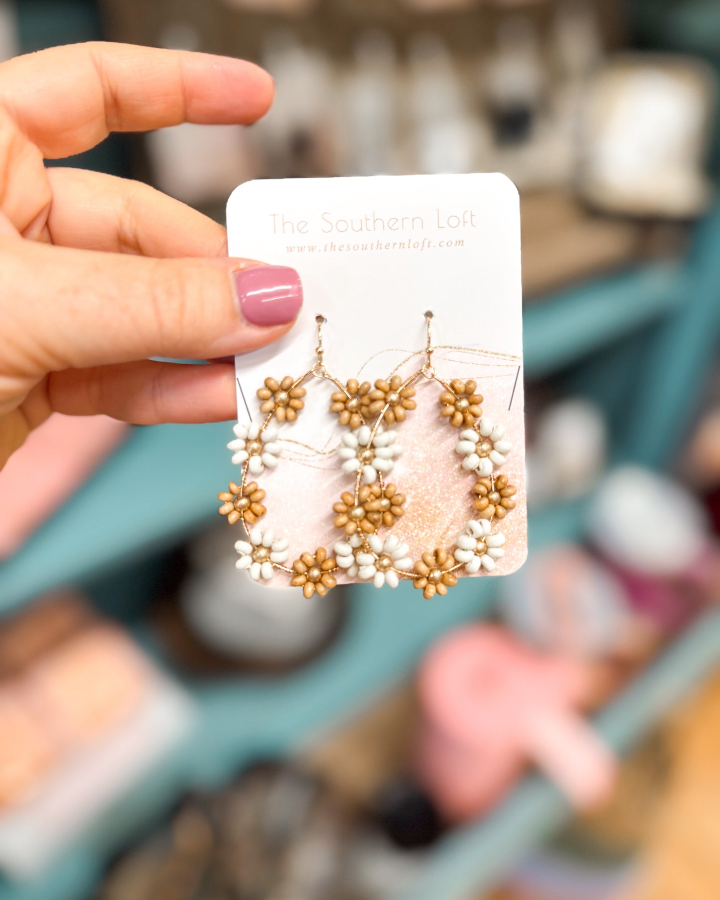 Hand holding a card with beaded earrings against a blurred background