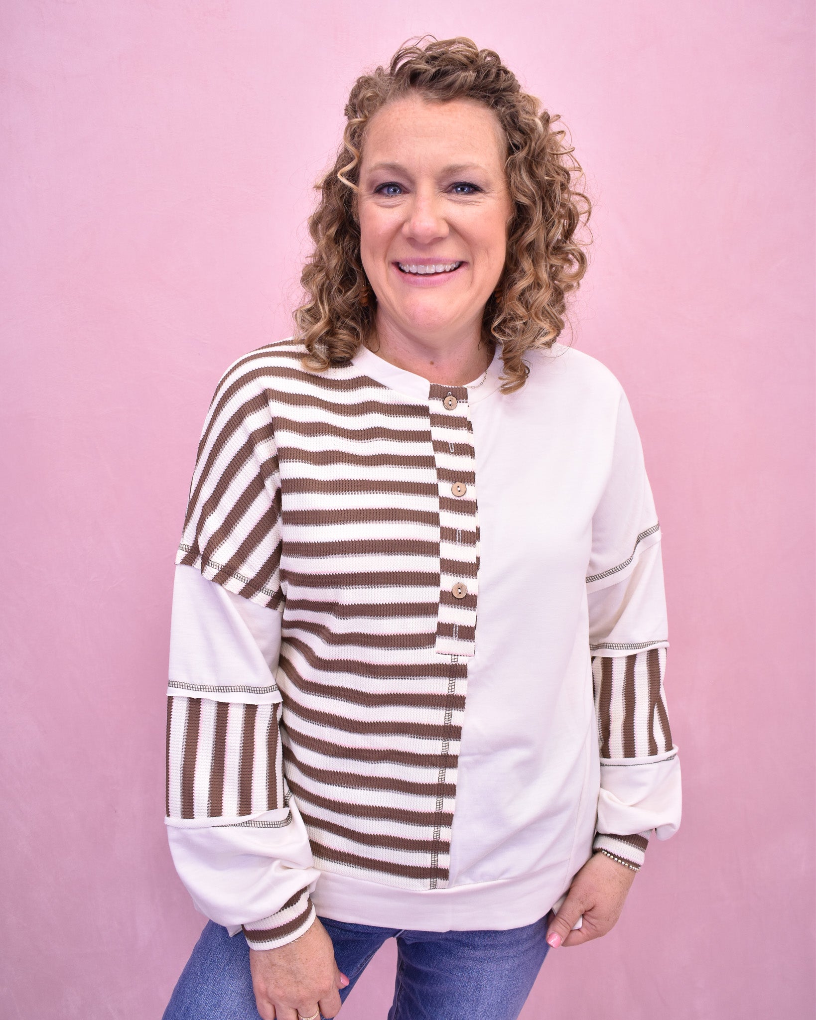 Woman wearing a white and brown striped shirt against a pink background