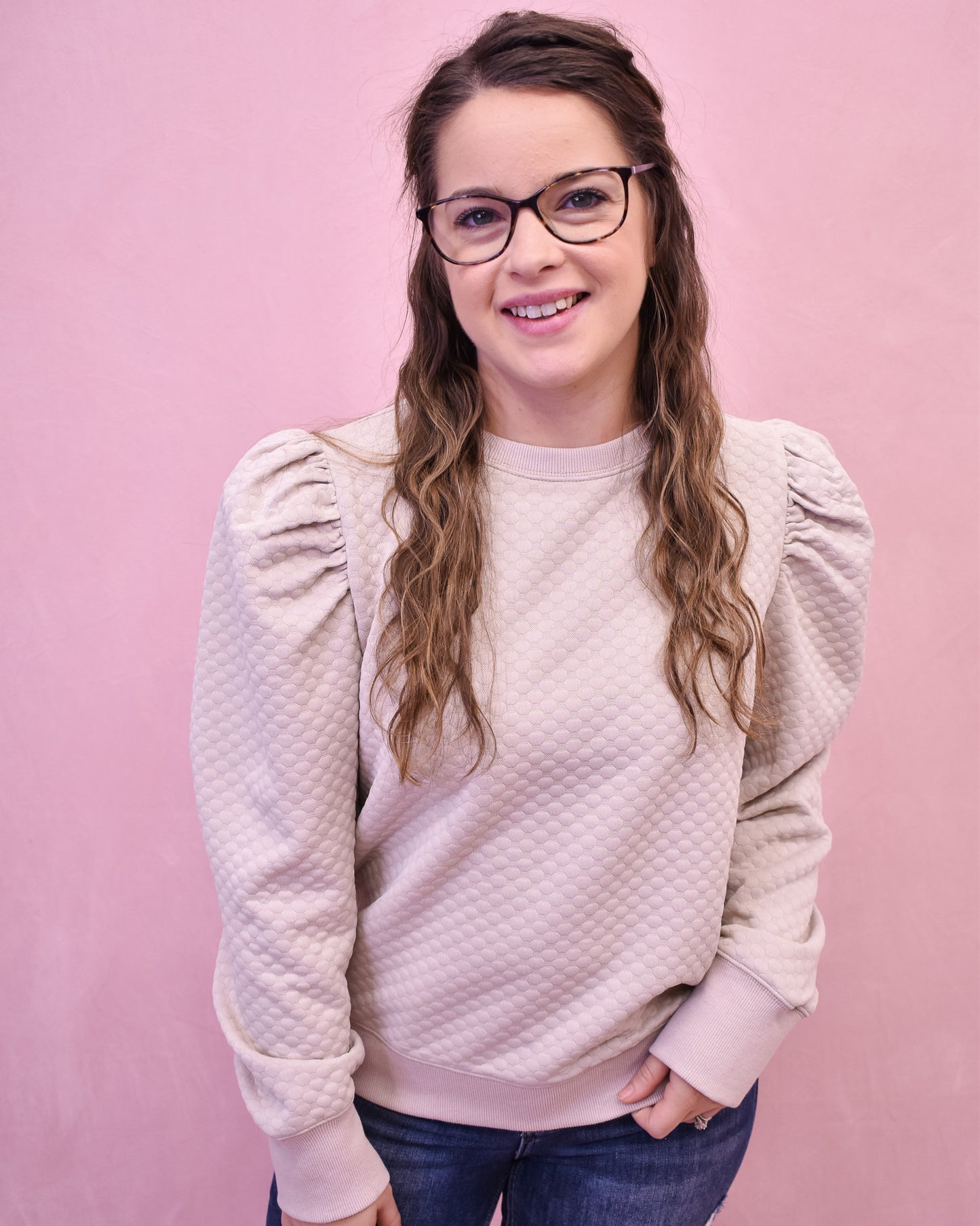 Person wearing a light pink textured sweater against a pink background