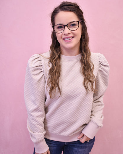 Person wearing a light pink textured sweater against a pink background