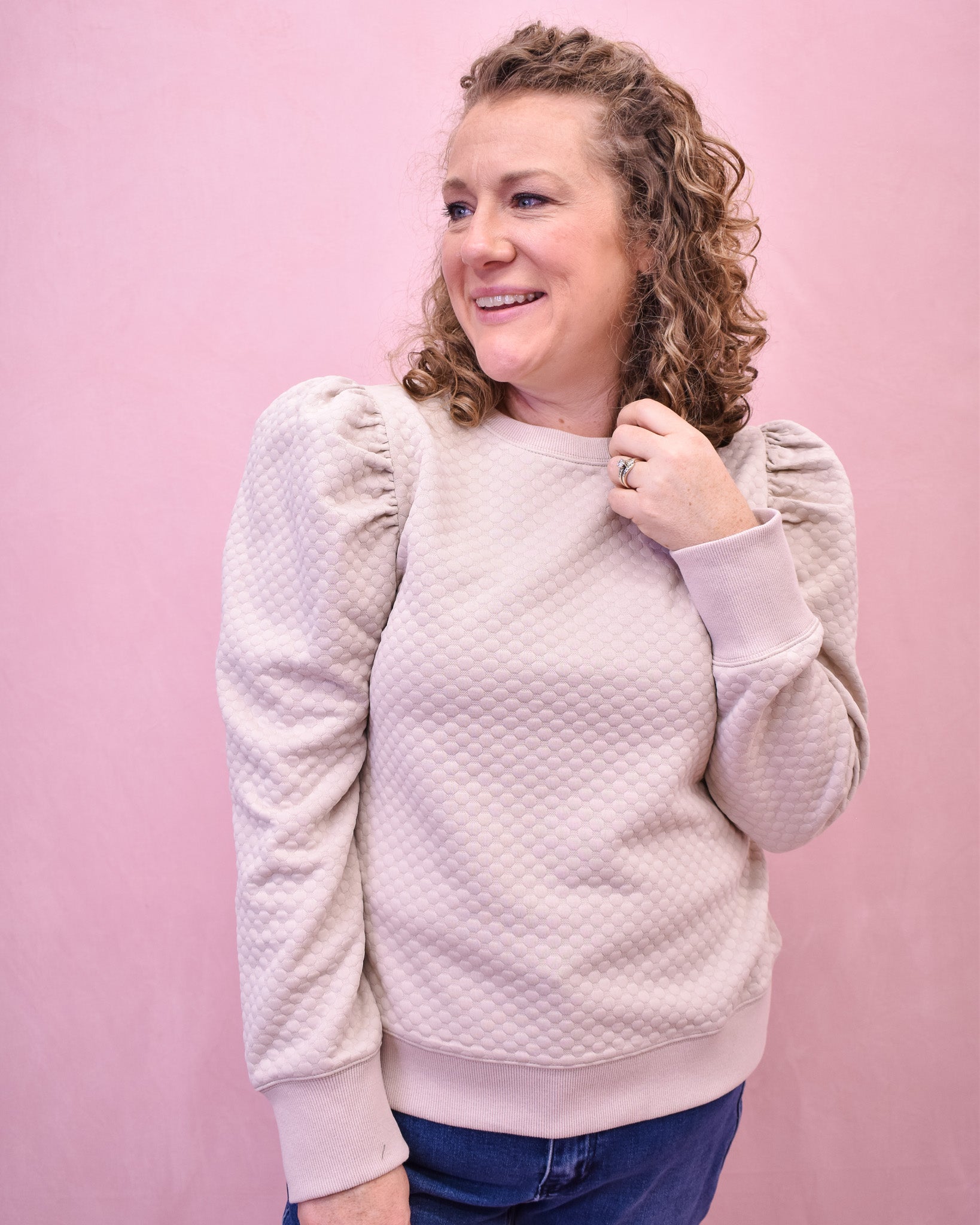 Woman wearing a textured light pink sweater against a pink background