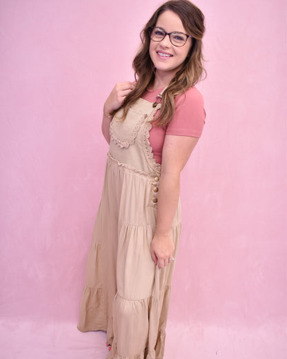 Woman wearing a pink top and beige dress against a pink background