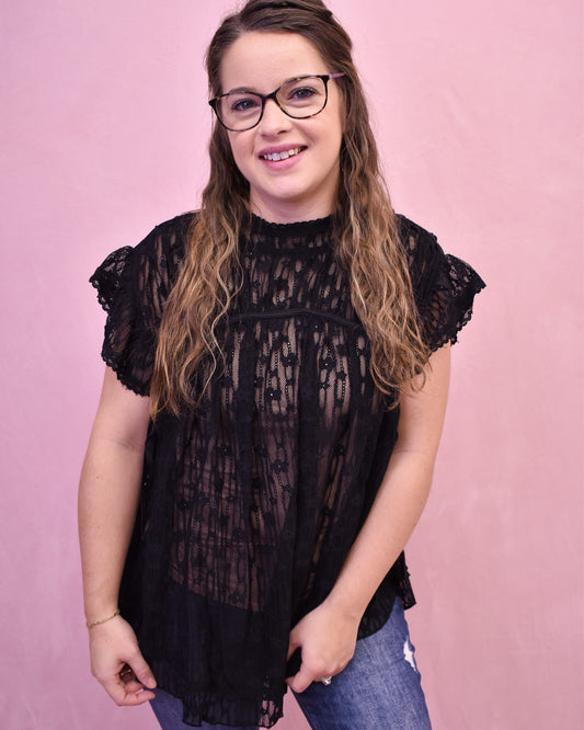 Woman wearing a black lace top against a pink background