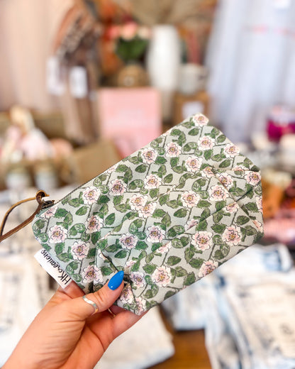 Floral-patterned pouch held by a hand with a blurred background