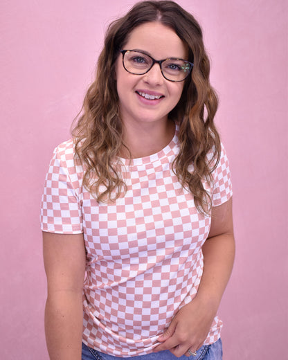 Woman wearing a pink and white checkered shirt against a pink background