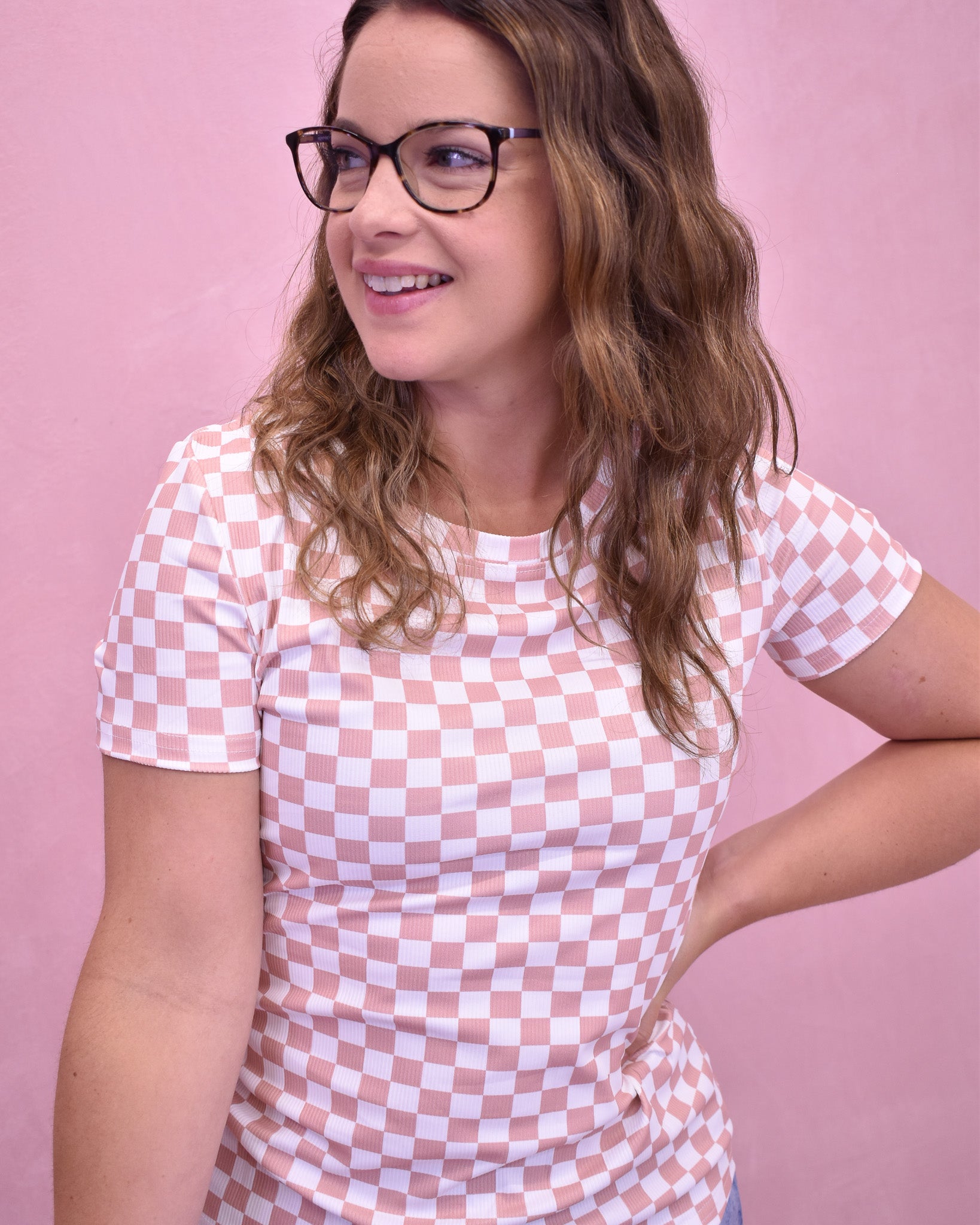 Woman wearing a pink and white checkered dress against a pink background