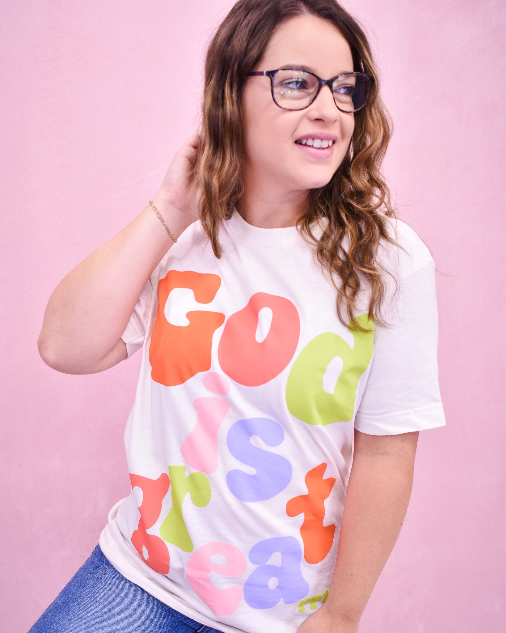 Person wearing a colorful t-shirt with text against a pink background
