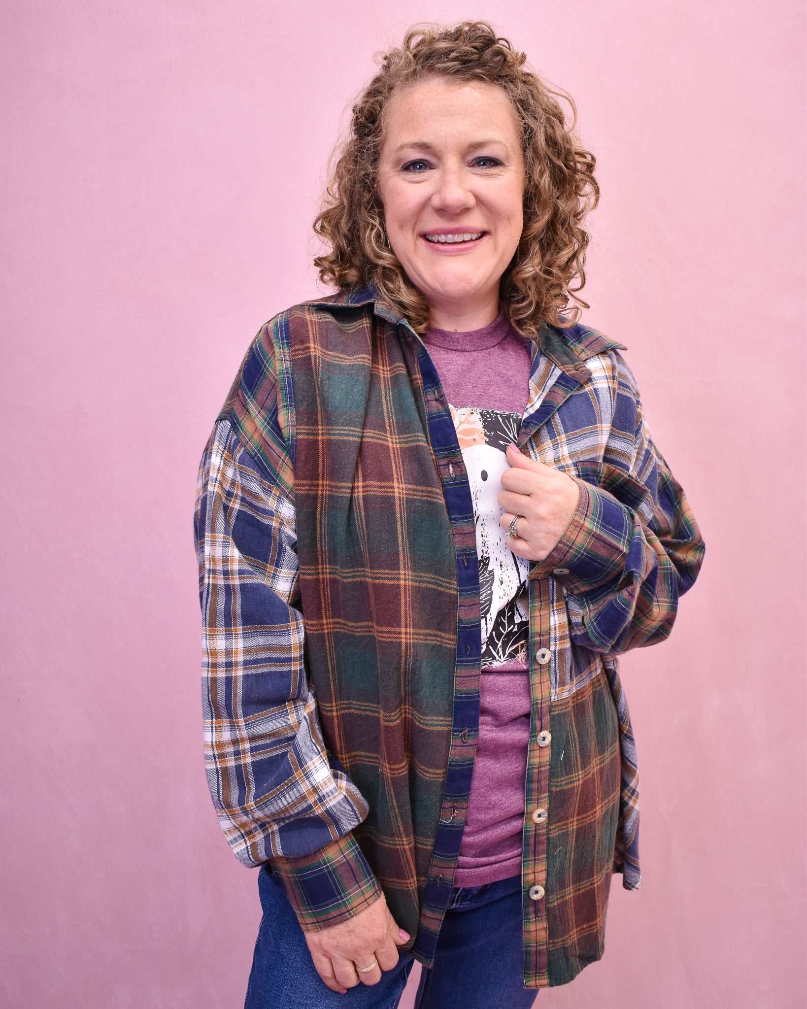 Person wearing a plaid shirt over a purple top on a pink background
