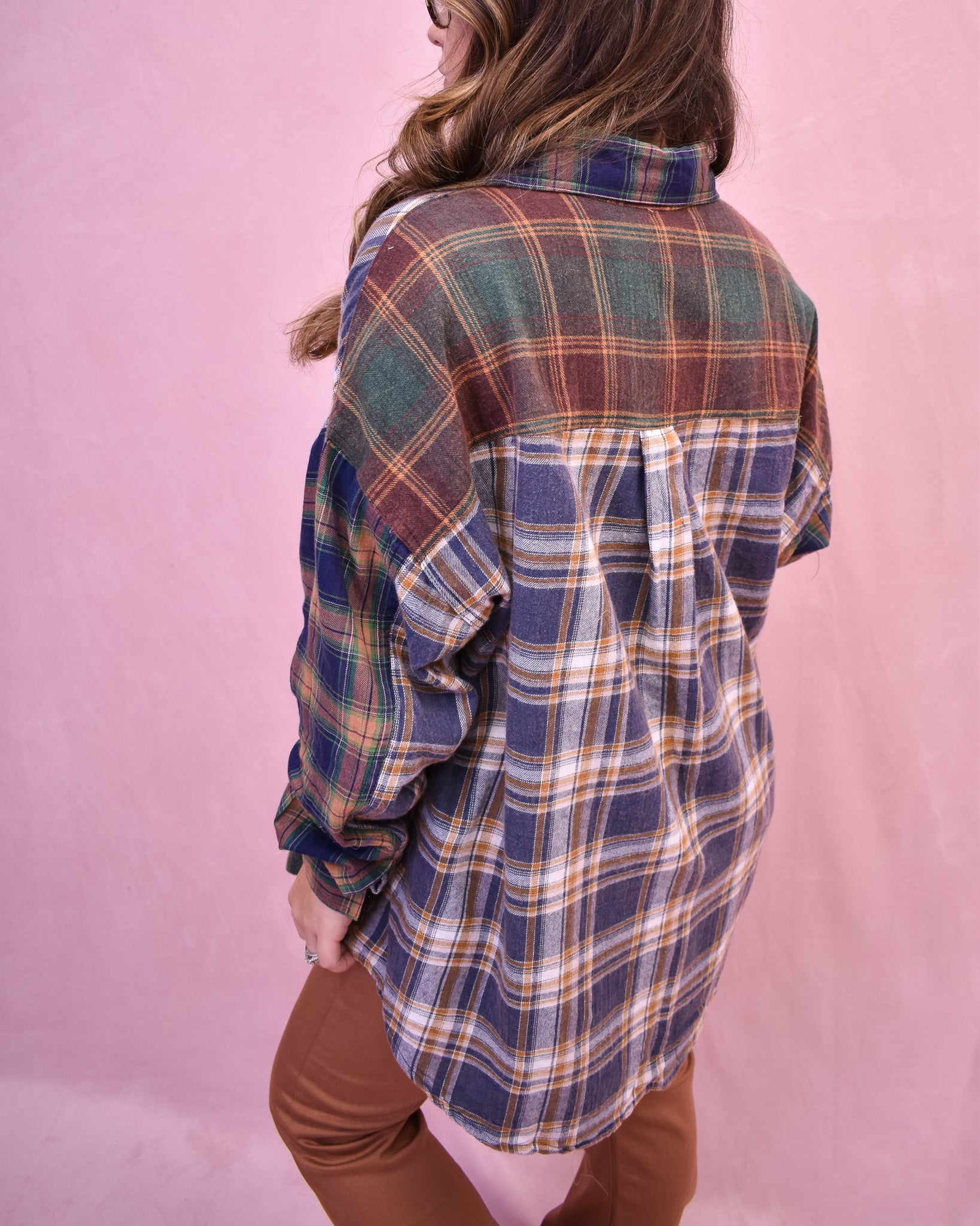 Person wearing a plaid shirt with a pink background