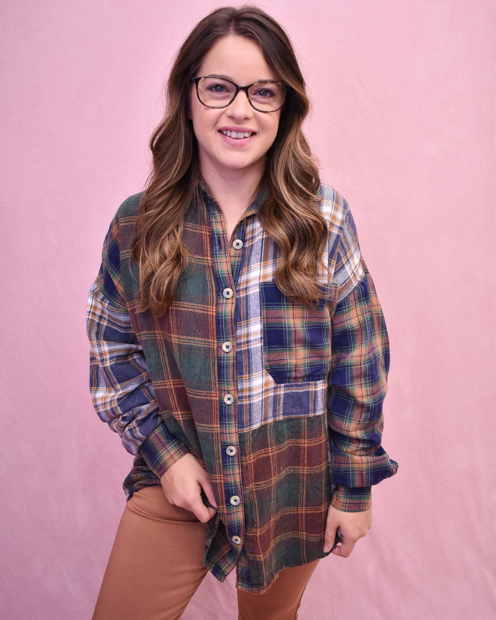 Woman wearing a plaid shirt and glasses against a pink background