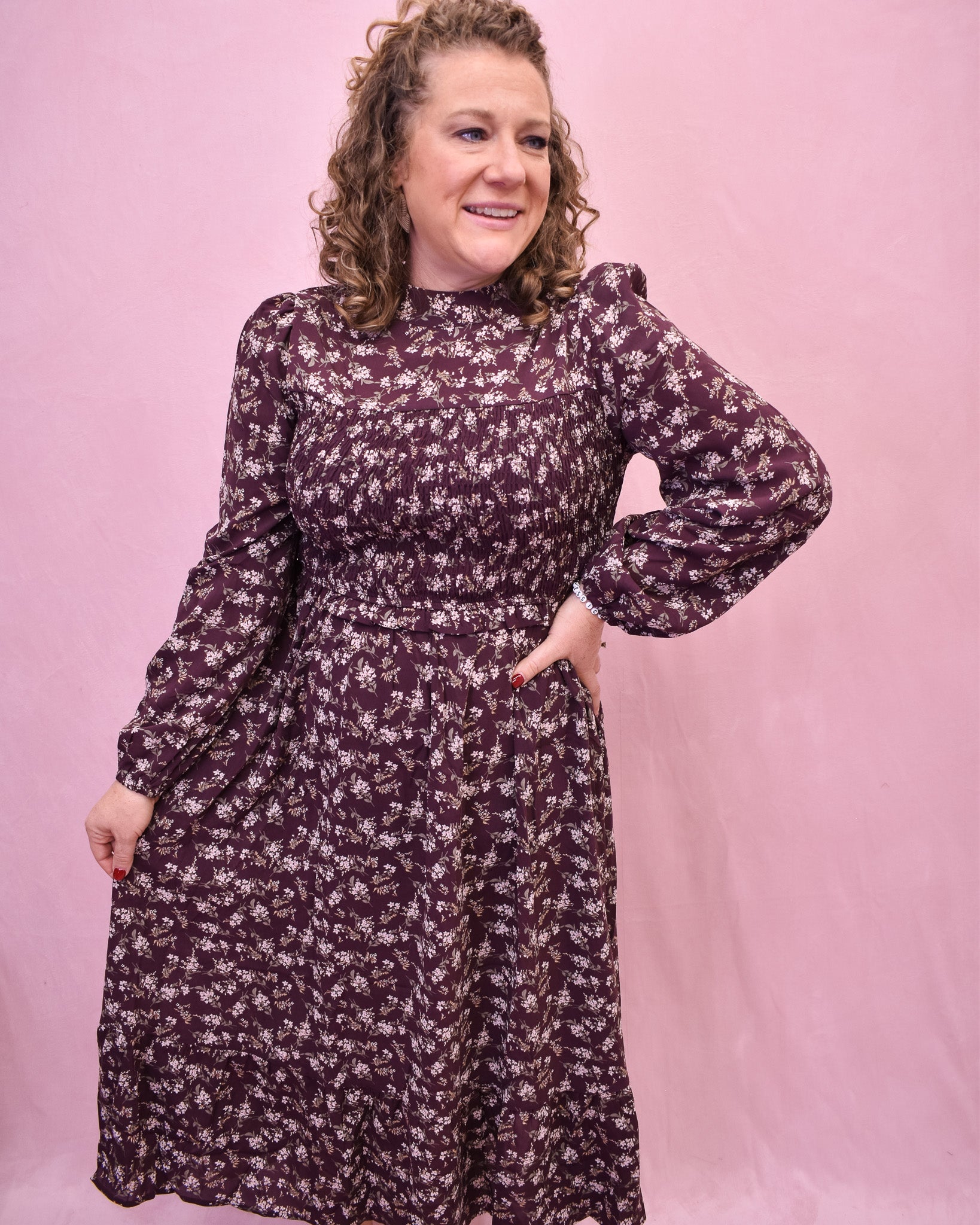 Woman wearing a floral dress against a pink background