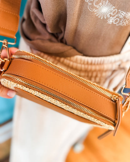 Close-up of a brown leather crossbody bag with gold zipper