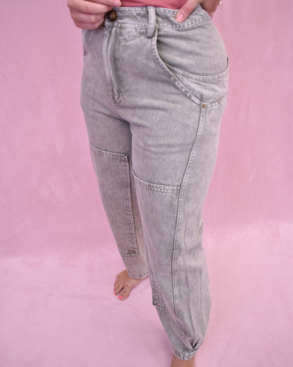 Gray jeans worn by a person on a pink background