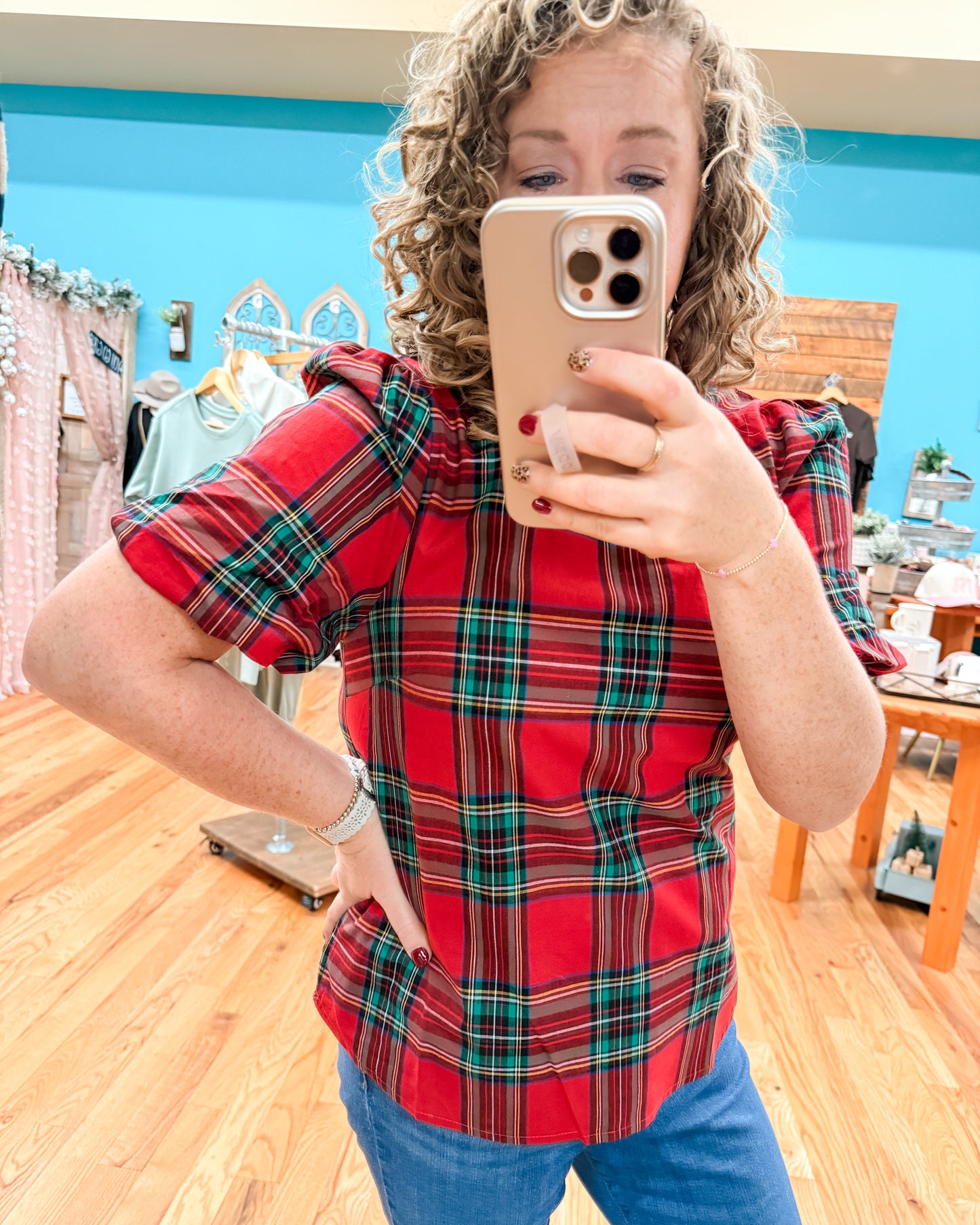 Person wearing a red plaid shirt taking a mirror selfie in a store.