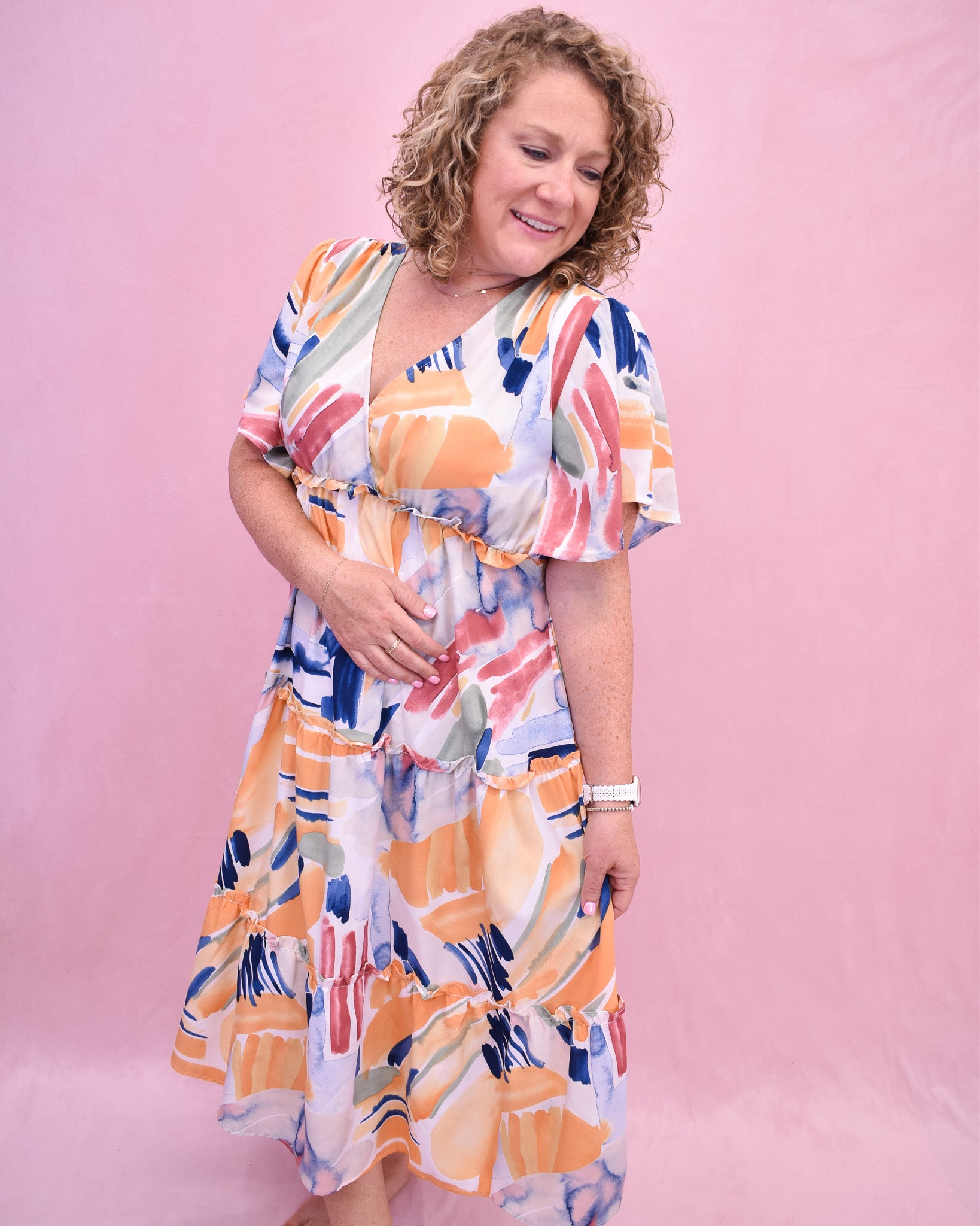 Woman wearing a colorful dress against a pink background
