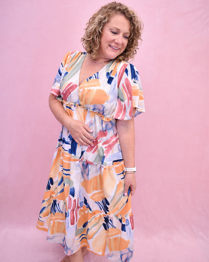 Woman wearing a colorful dress against a pink background